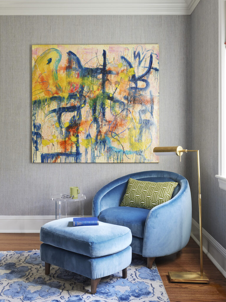 Room corner designed by chicago interior designer featuring a beautiful blue round armchair with a matching footrest and a sage green cushion. The setup includes a gold-gilded sculptural reading light and contemporary artwork on the wall, creating a cohesive composition.