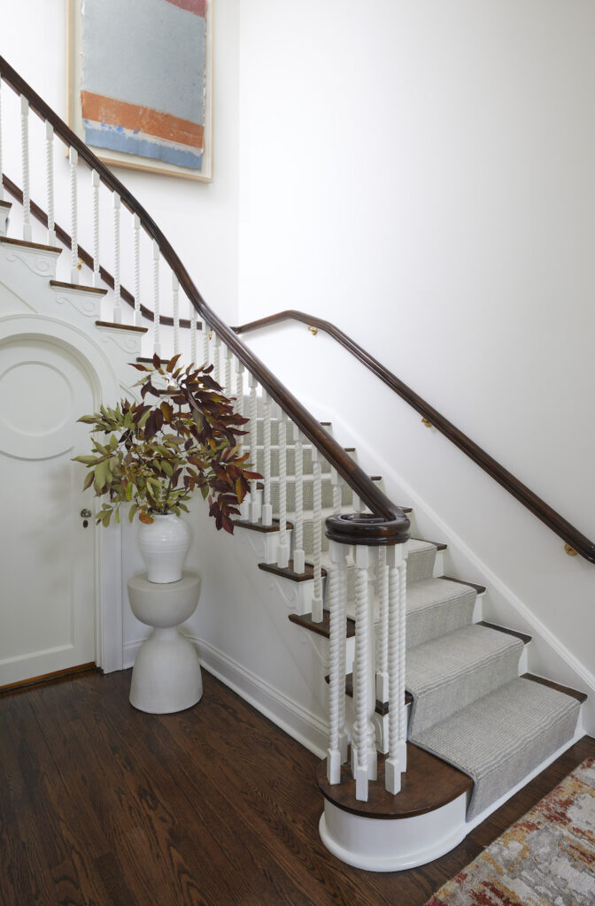 A simple yet elegant white stairway that celebrates the building's architectural elements. Dark wood handrails complement the white hues.