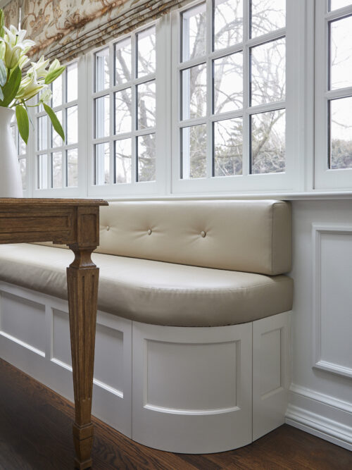Tan and white banquette underneath windows in a dining room