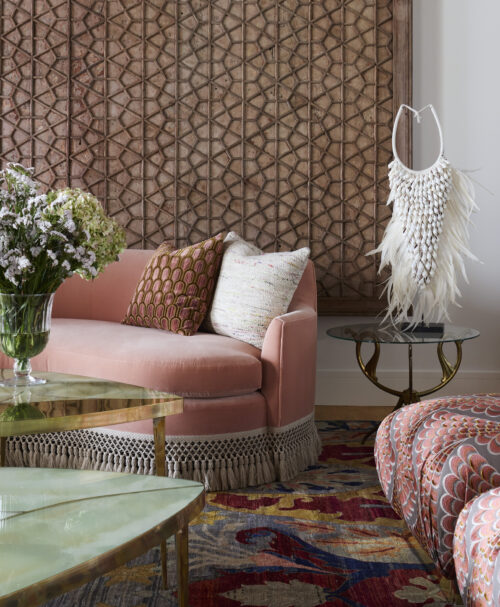 Interior design studio featuring pink couch, throw pillows, patterned rug, and accessories