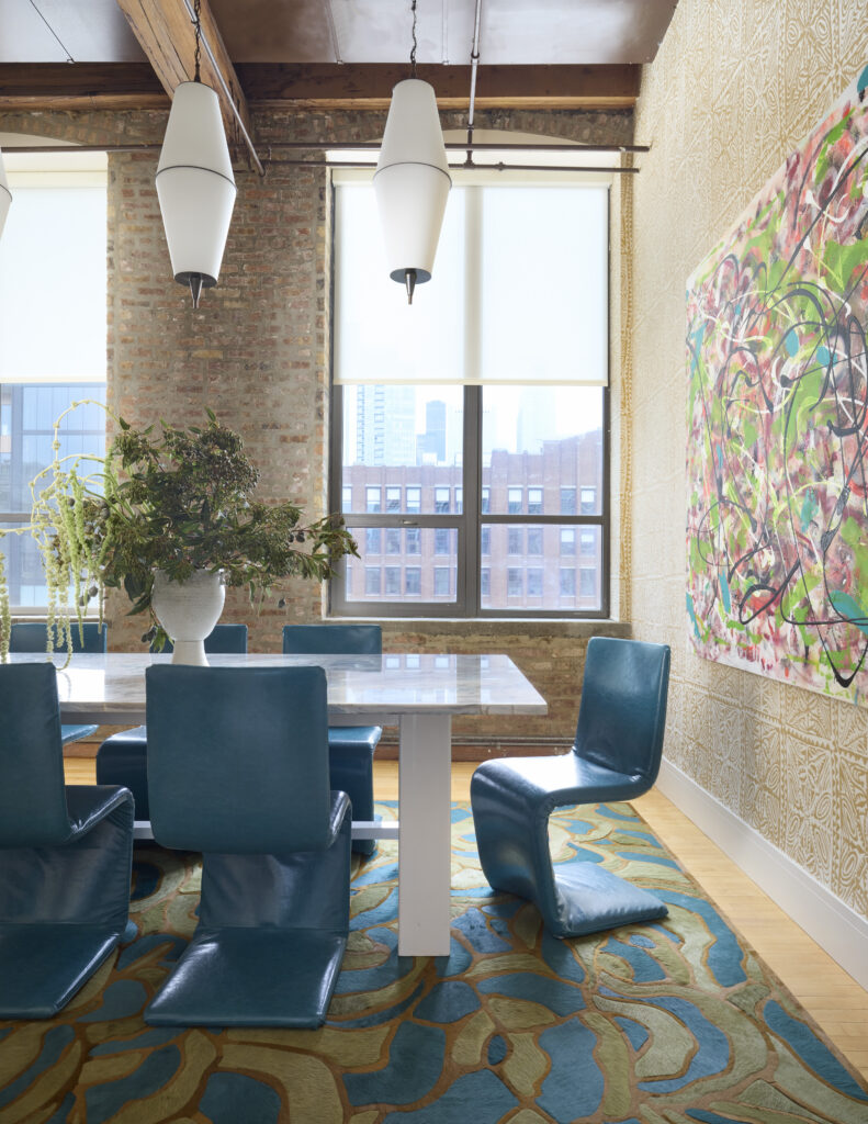 Interior design studio conference room featuring blue chairs, a conference table, art, and a view of Chicago