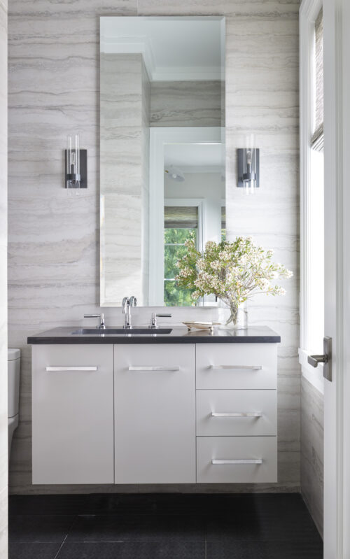 Primary bathroom with white cabinetry, marble vanity, and sconces next to the mirror.