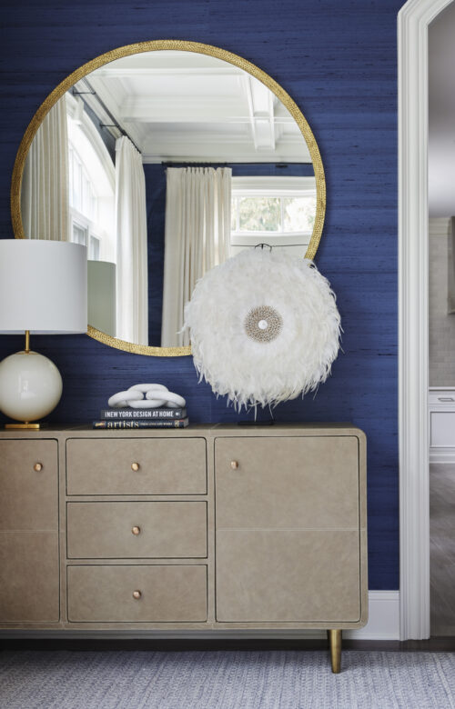 Living room with console, white lamp, round mirror, and decor.