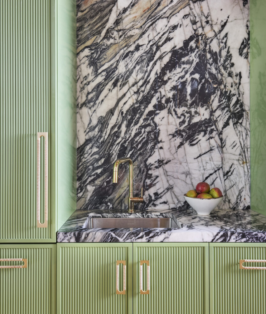 Kitchen with marble backplash, green cabinetry, and handcrafted hardware